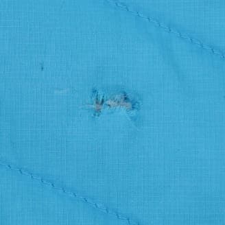 青色の生地に小さな割け目があり、中の繊維が見えているクローズアップ画像