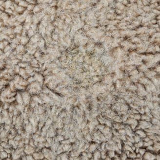 修理後の同じ茶色のフリース生地のクローズアップ画像。穴が目立たなくなり、補修された部分が周囲の生地と調和している。