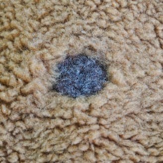 茶色のフリース生地に小さな穴があり、中の素材が見えているクローズアップ画像。