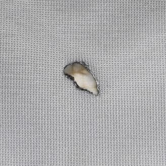 灰色の生地に小さな穴があり、中の素材が見えているクローズアップ画像。