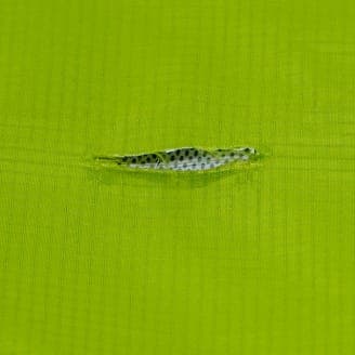 緑色の生地に小さな裂け目があり、中のメッシュが見えているクローズアップ画像